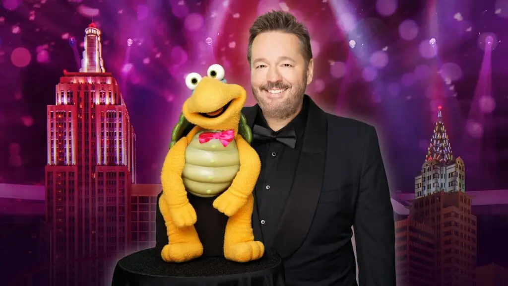 Terry Fator in tuxedo with Winston the Impersonating Turtle puppet against theatrical backdrop