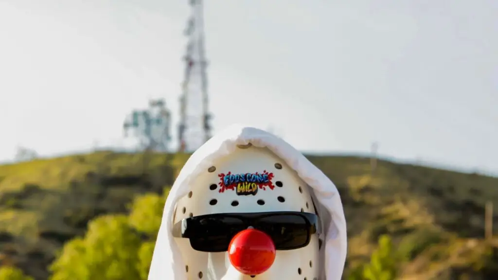 Foos Gone Wild performer in signature hockey mask with band logo, hillside backdrop