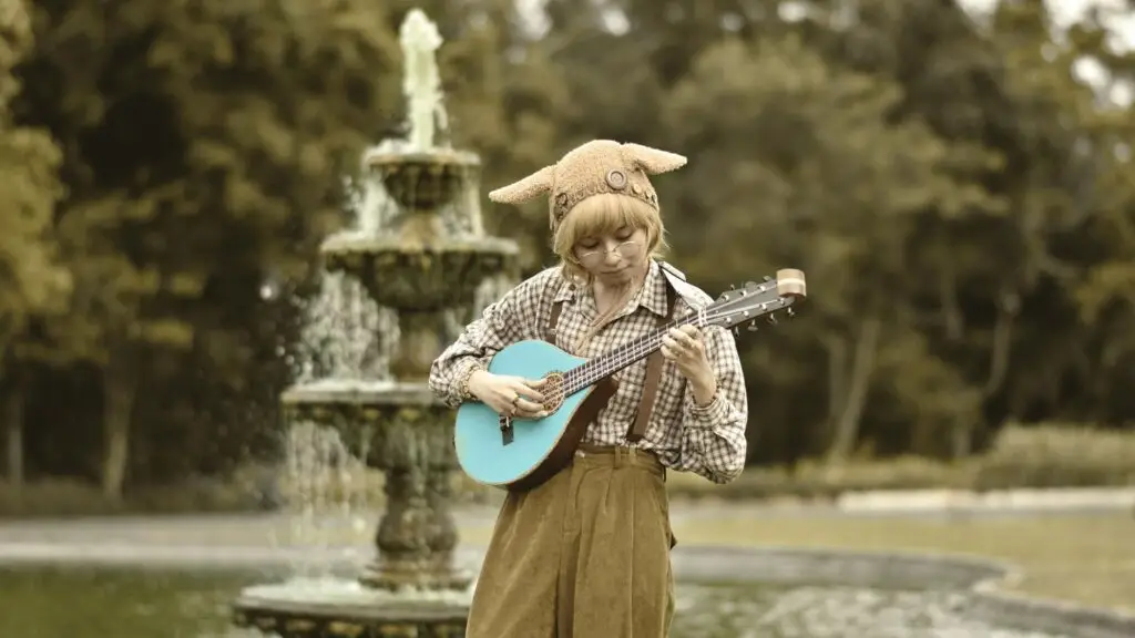 Yaelokre playing the custom Meadowlark instrument outdoors near a garden fountain
