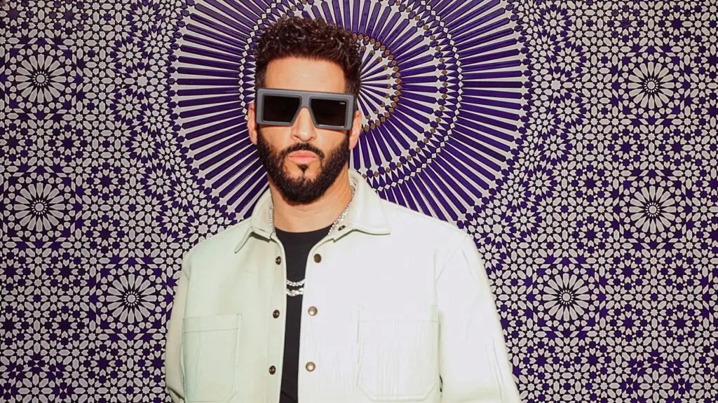 Jon B. in white jacket and square sunglasses, official press photo for The Chozen Tour 2026