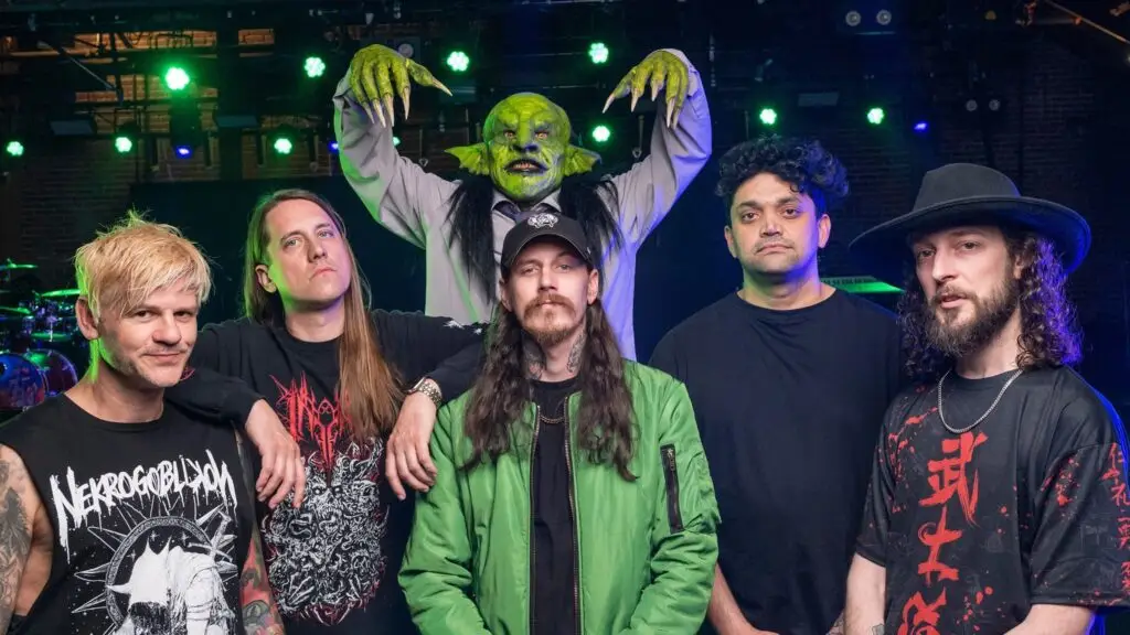 Nekrogoblikon band members with John Goblikon goblin mascot on stage, 20 Years anniversary tour