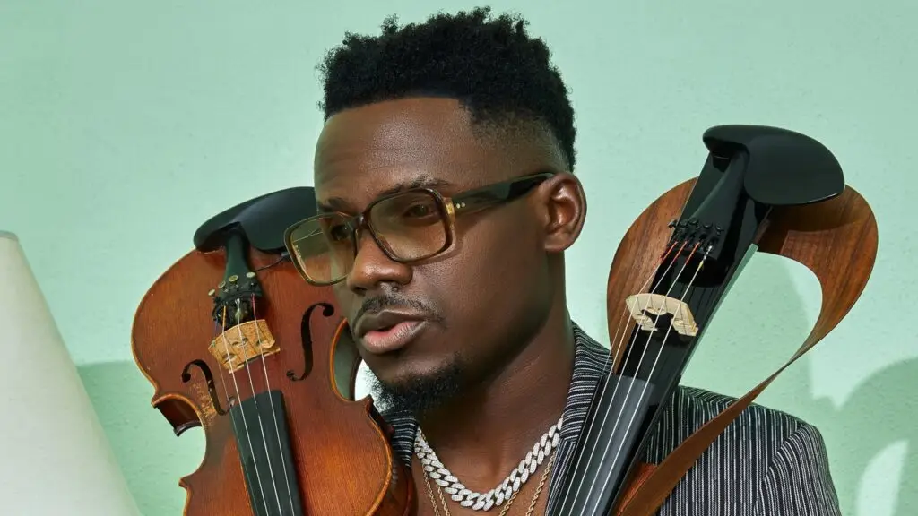 Demola holding acoustic and electric violins, studio press photo, mint-green background