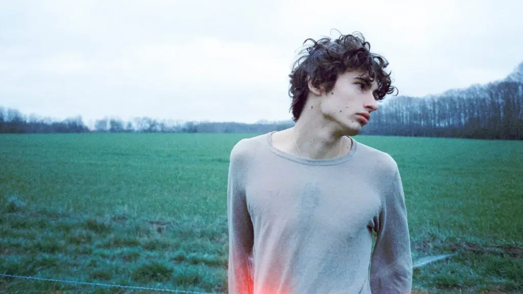 glaive standing in a rural field on an overcast day, press photo for God Save the Three Tour