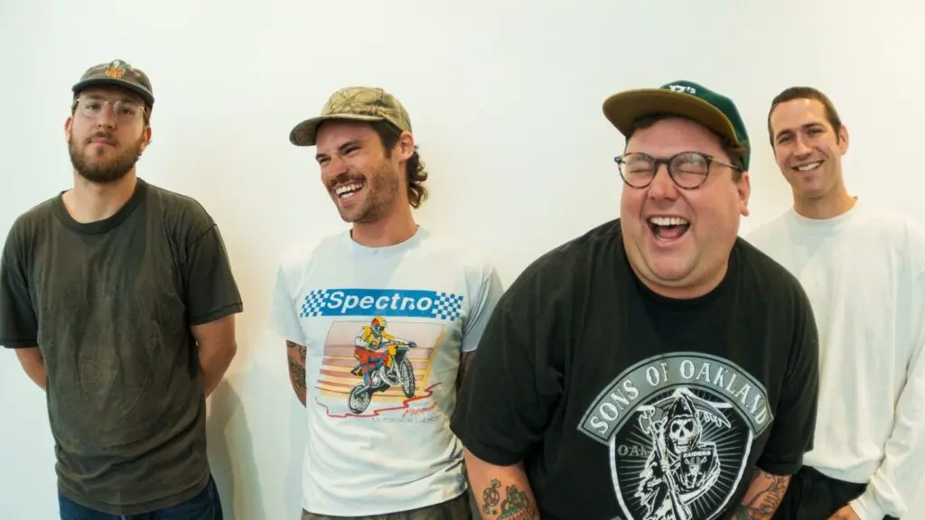 Mom Jeans four-piece band press photo — Eric Butler, Bart Thompson, Austin Carango, Sam Kless laughing against white backdrop