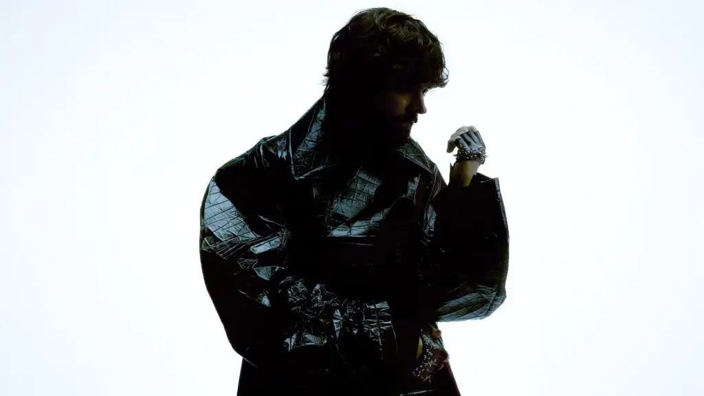 Madeon in dramatic Victory era press photo, dark silhouette in black jacket against light background