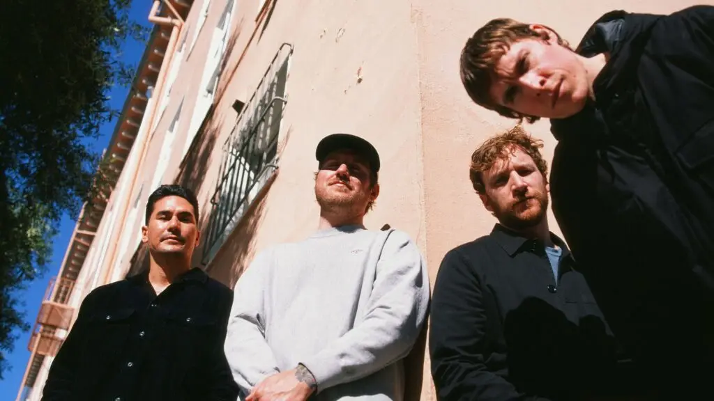 The Story So Far performing outdoors — four-piece pop-punk band press photo against a sun-lit stucco wall