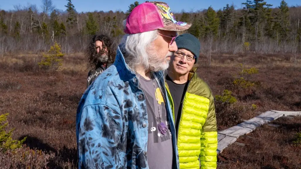 Dinosaur Jr. — J Mascis, Lou Barlow, and Murph pose outdoors in a marsh landscape